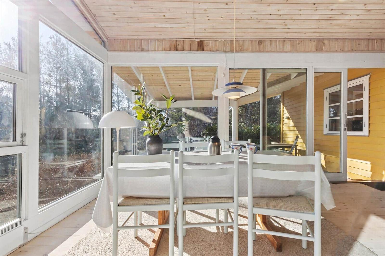 Esszimmer mit Tisch, Stühlen und großem Fensterblick auf Wald
