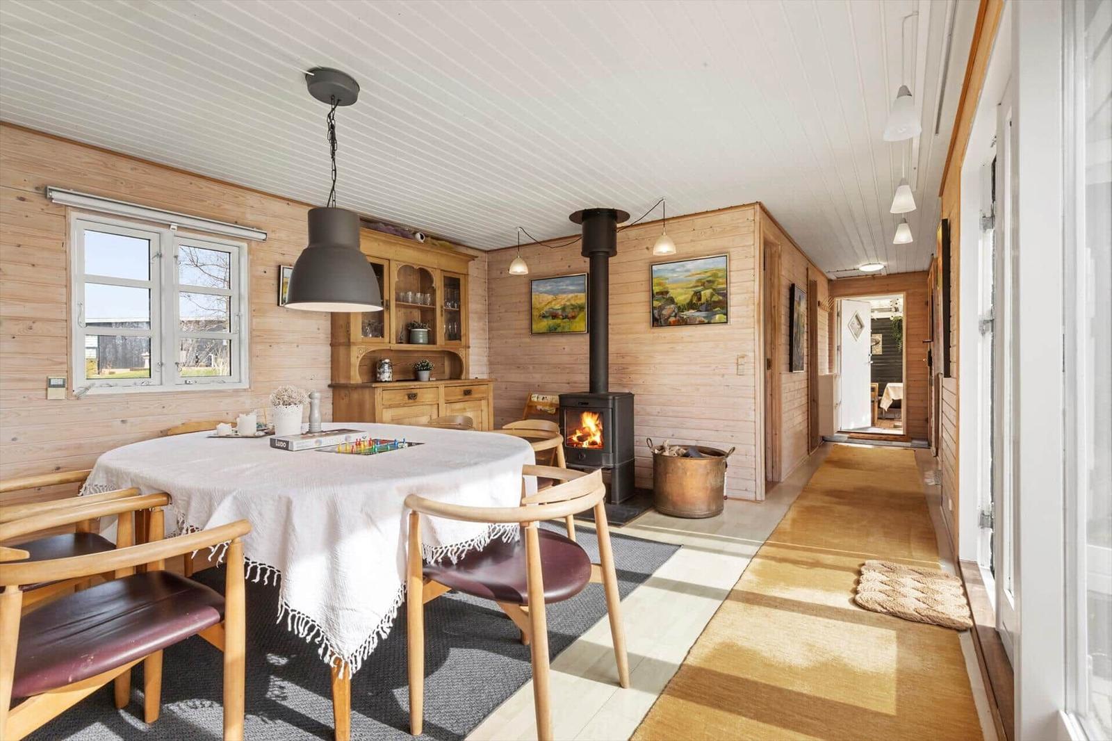 Esszimmer mit Holzwand, Esstisch, Kamin und Bildern an der Wand.