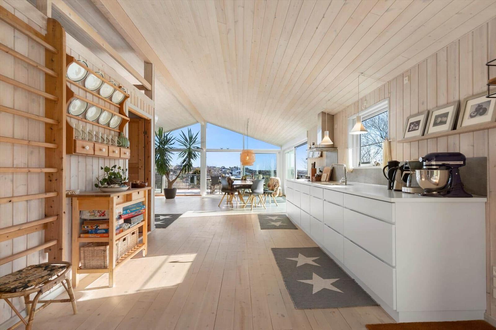 Küche mit weißem Schrank und Holzdecke. Blick auf Essbereich mit Tisch und Stühlen.