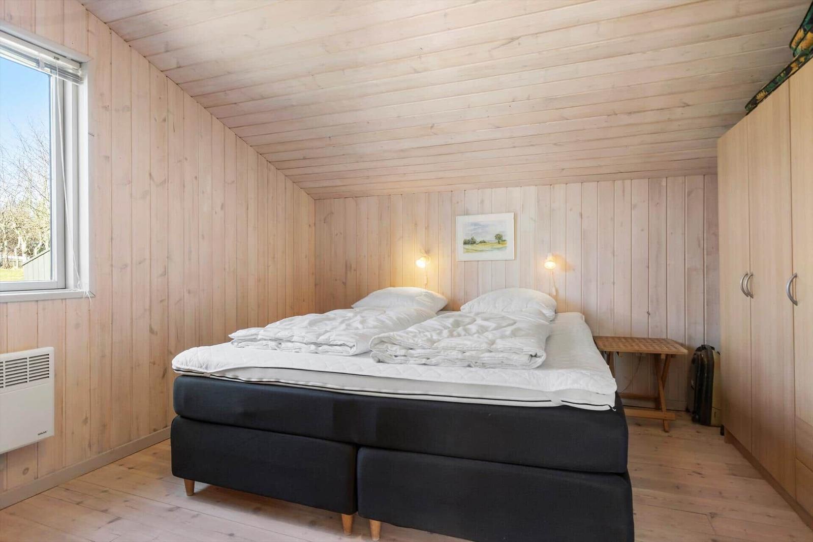 Schlafzimmer mit Holzwand, Bett und Kleiderschrank