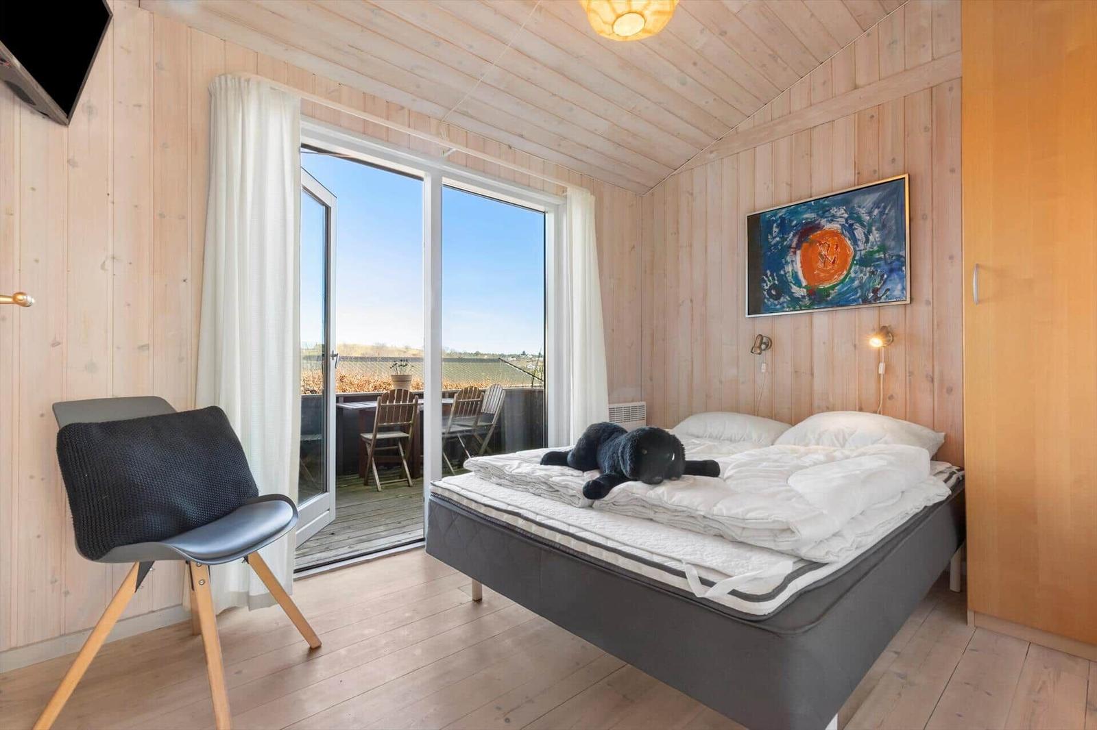Schlafzimmer mit Bett, Stuhl und Balkonansicht.