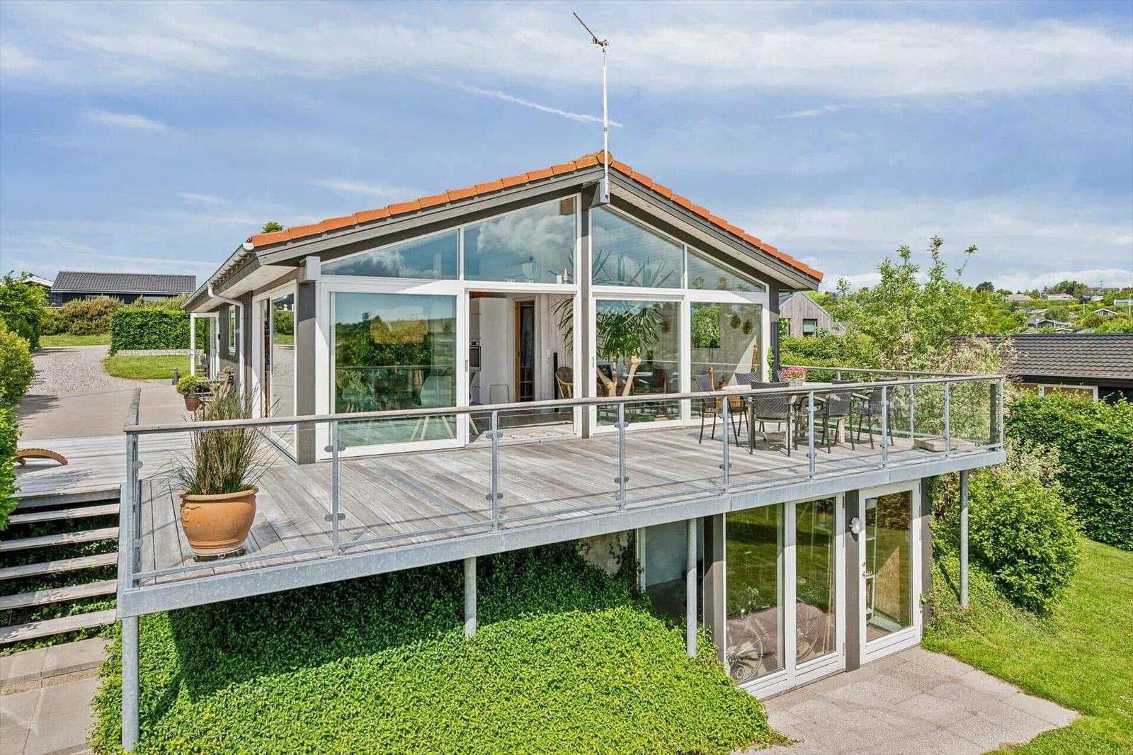 Moderne Villa mit großem Balkon und Glasfassade. Terrasse mit Sitzgelegenheiten.