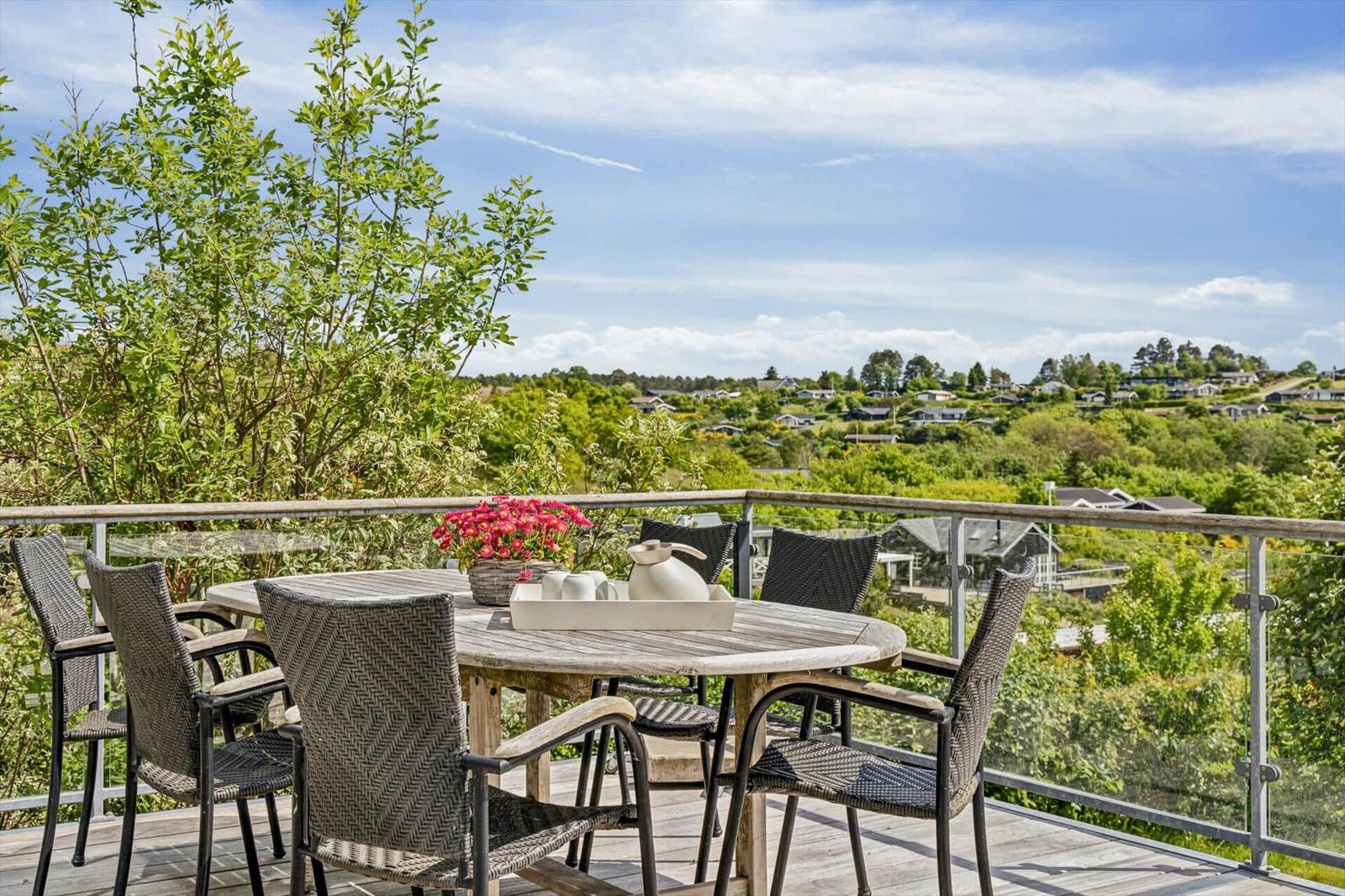 Terrasse mit Tisch und Stühlen, Blick auf grüne Landschaft.