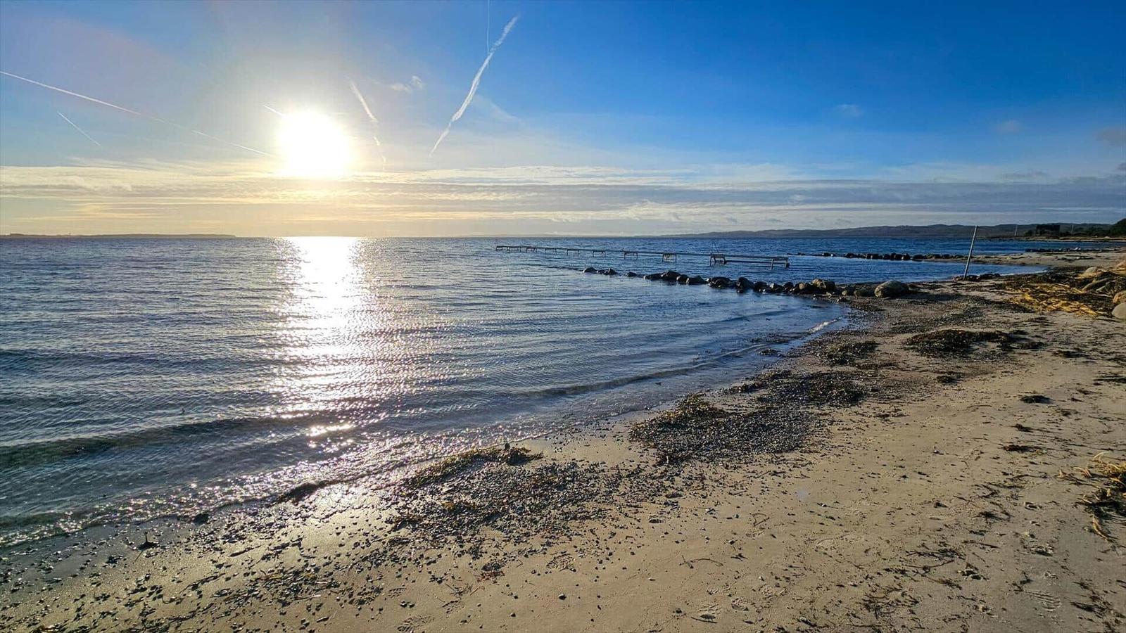 Sonnenlicht spiegelt sich auf dem Wasser. Strand mit Steinen und Wellen.