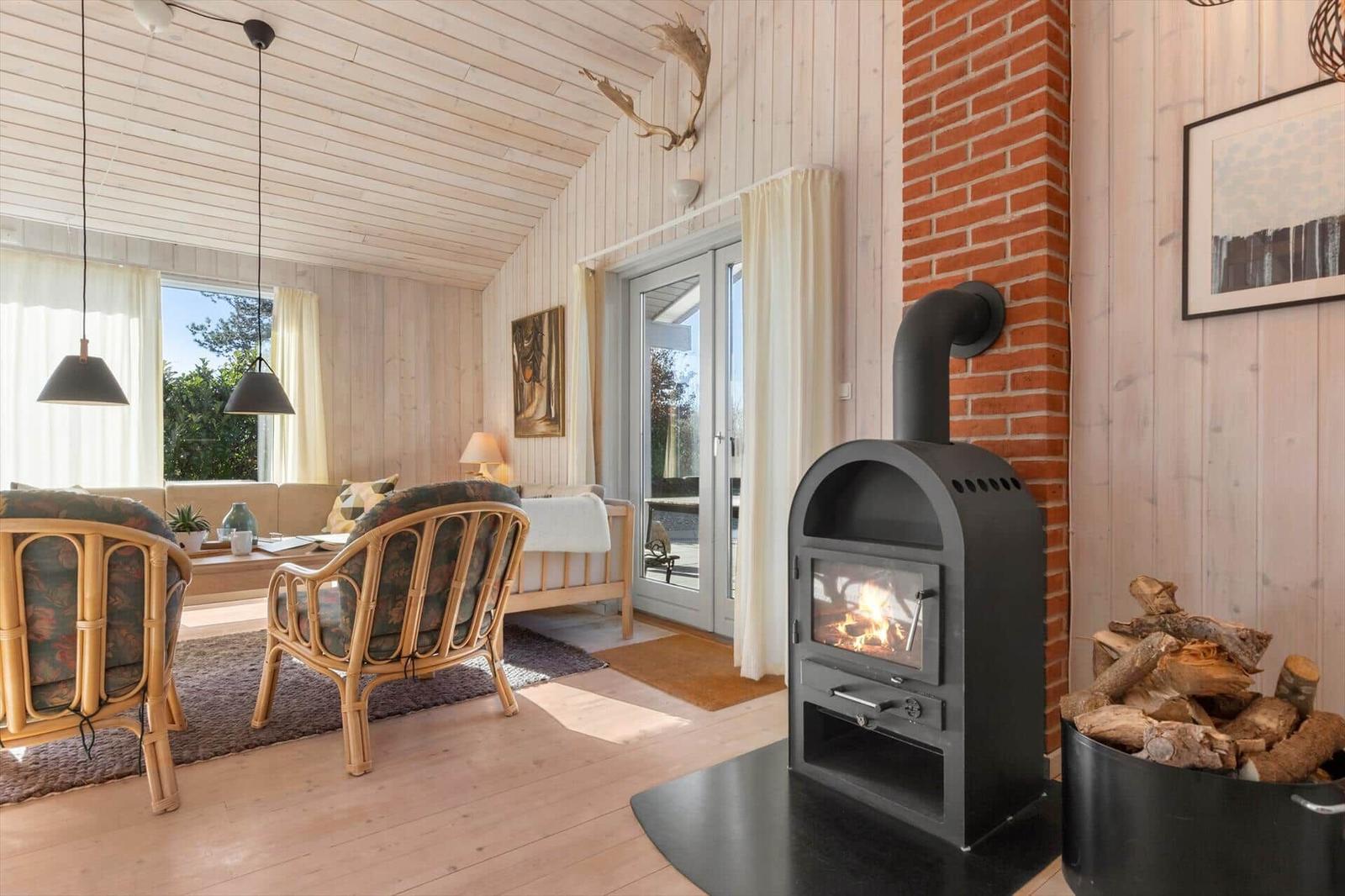 Wohnzimmer mit Kaminofen, Holzdielen und Sitzgelegenheiten.