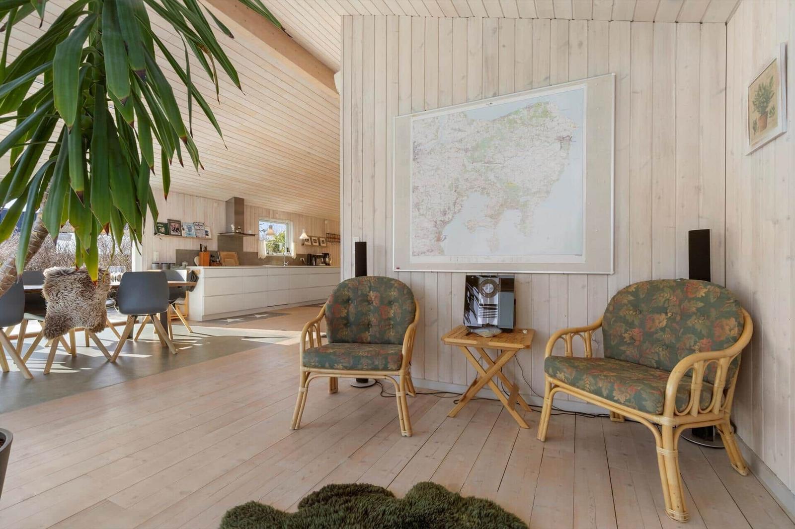 Wohnraum mit Rattanmöbeln, Karte an der Wand und Blick in die Küche.