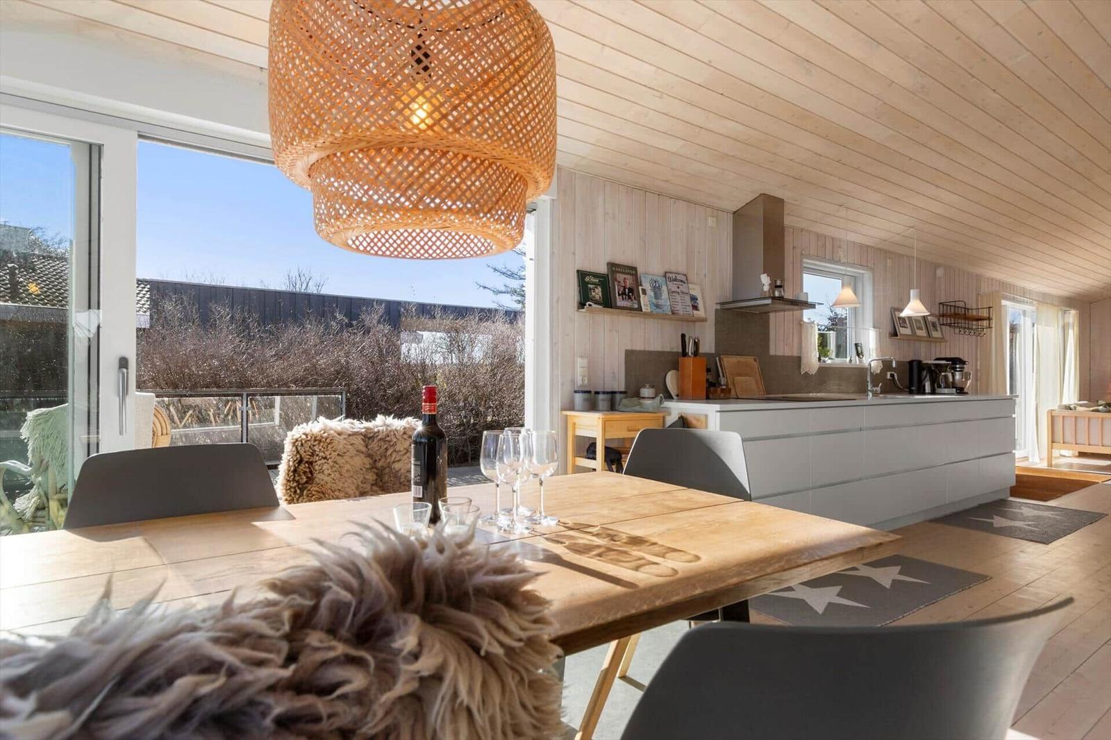 Essbereich mit Holztisch, Stühlen und Blick auf Balkon. Küche mit Arbeitsplatte und Küchengeräten.