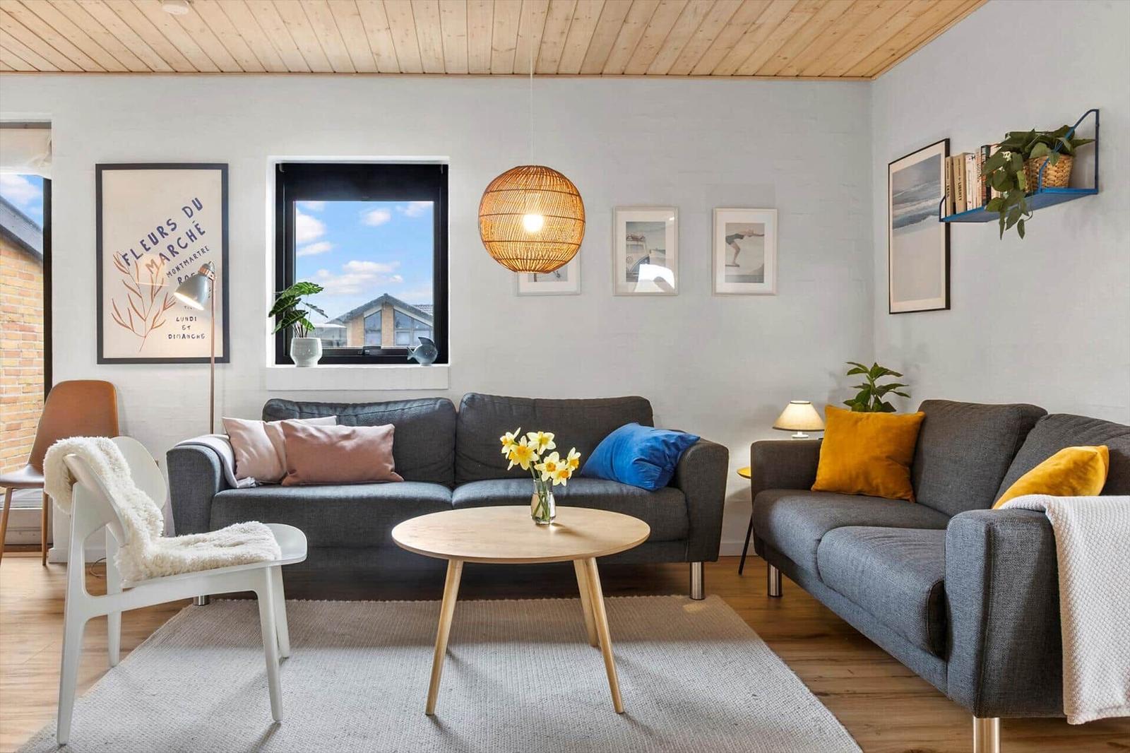 Wohnzimmer mit zwei Sofas, runden Tisch und Holzdecke.
