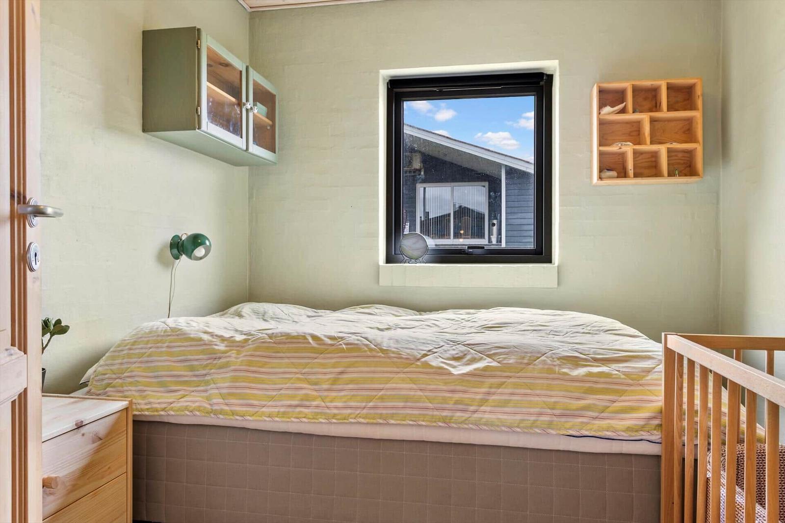 Schlafzimmer mit Bett, Fenster und Holzregal.