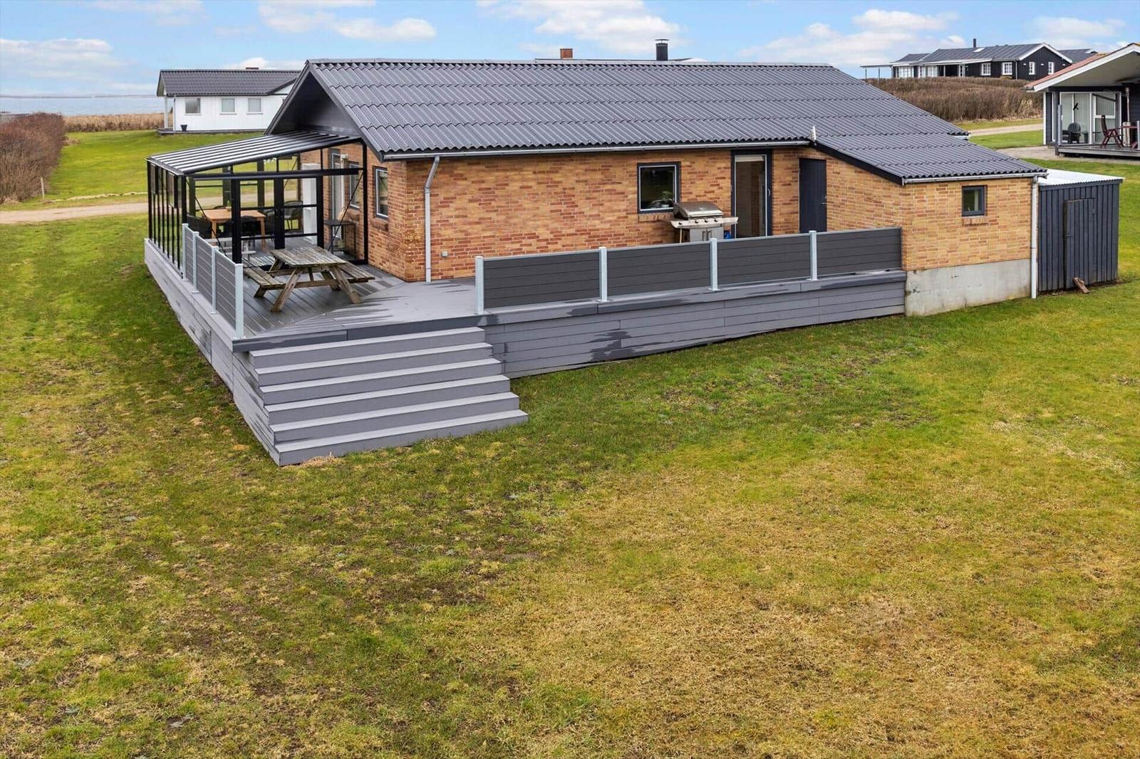 Haus mit Terrasse, Grill und Sitzgelegenheit im Freien.