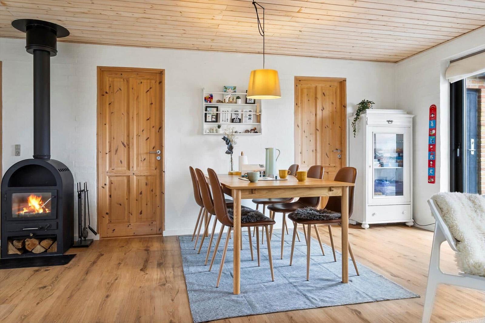 Esszimmer mit Holztisch, Stühlen und Kaminofen.