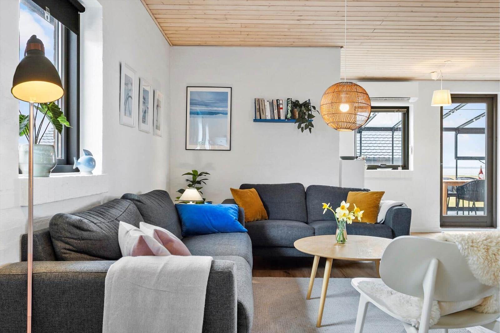 Wohnzimmer mit grauem Sofa, runden Tisch und Holzdecke.