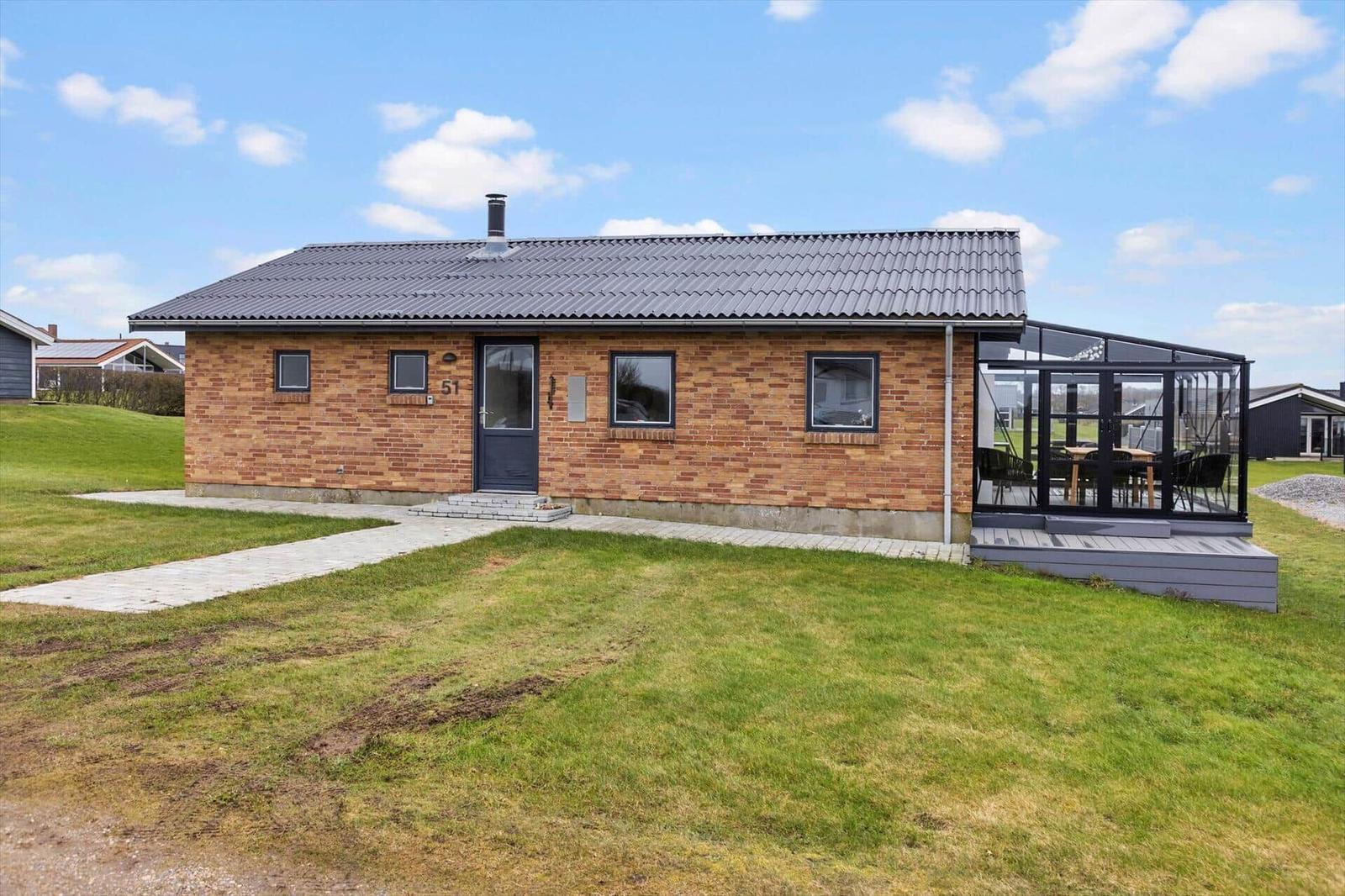 Ein Haus mit Backsteinfassade und Glasveranda im Freien.