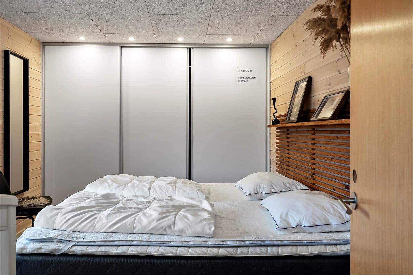 Schlafzimmer mit Bett, Schrank und Holzwand