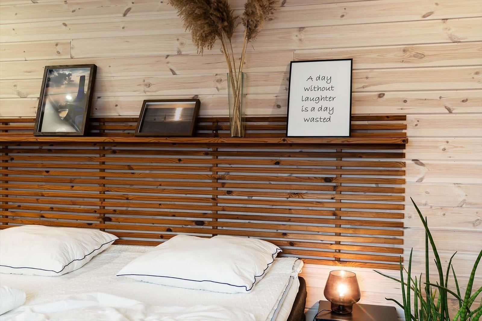 Schlafzimmer mit Holzwand, Bett und Dekoration.