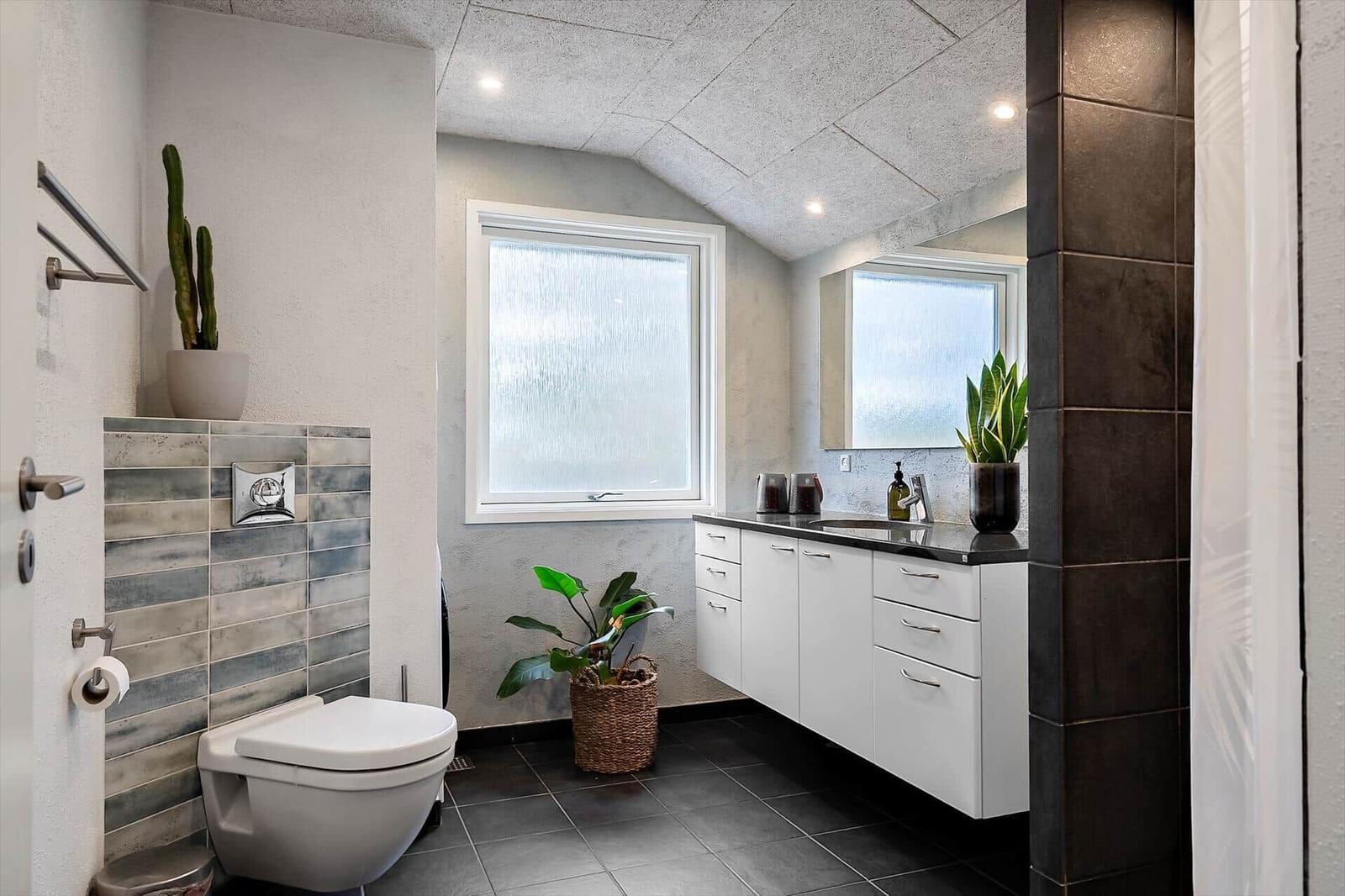 Badezimmer mit Toilette, Waschbecken und Pflanzen