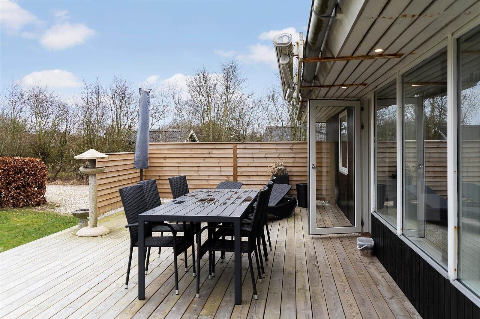 Terrasse mit Tisch und Stühlen, Holzdecke, Garten und Schutzzaun.