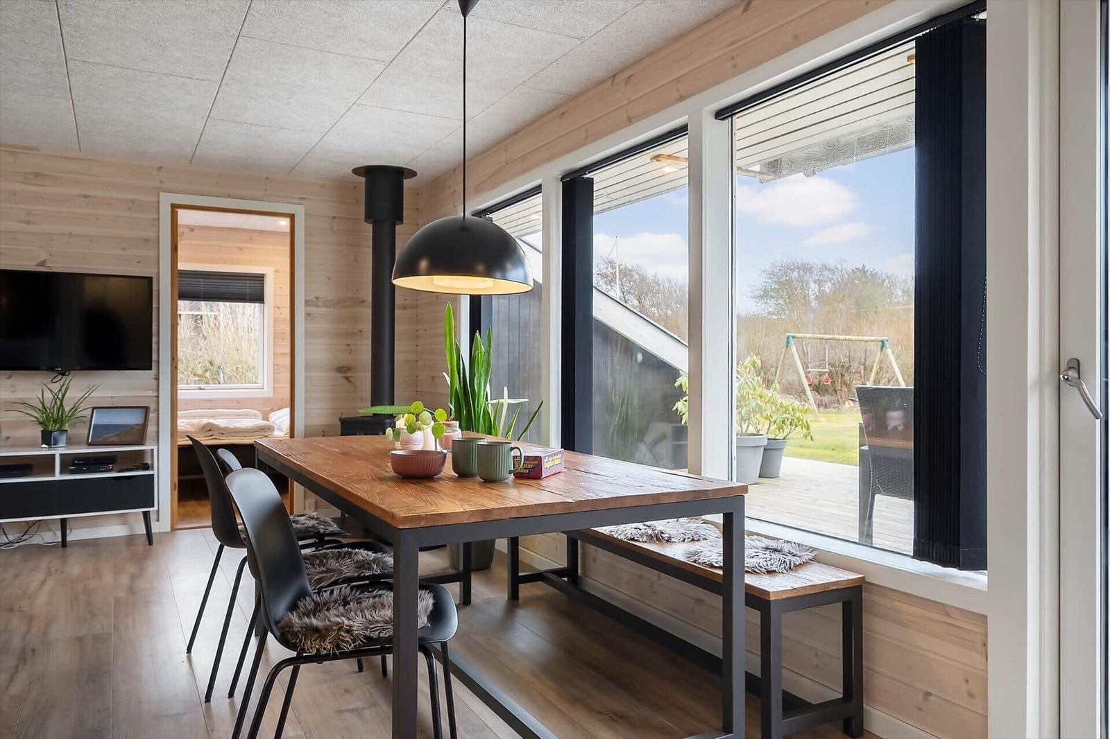 Essbereich mit Tisch, Stühlen und Fensterblick auf Terrasse.