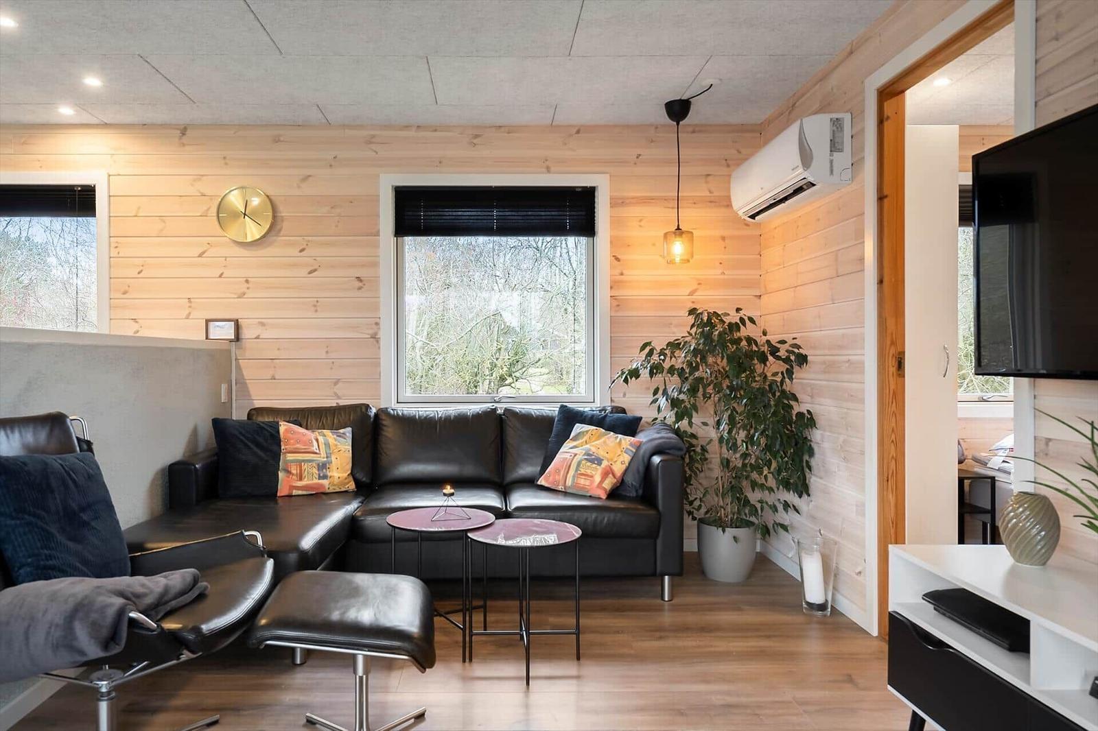 Wohnzimmer mit Ledersofa, Pflanzen und Fernseher.