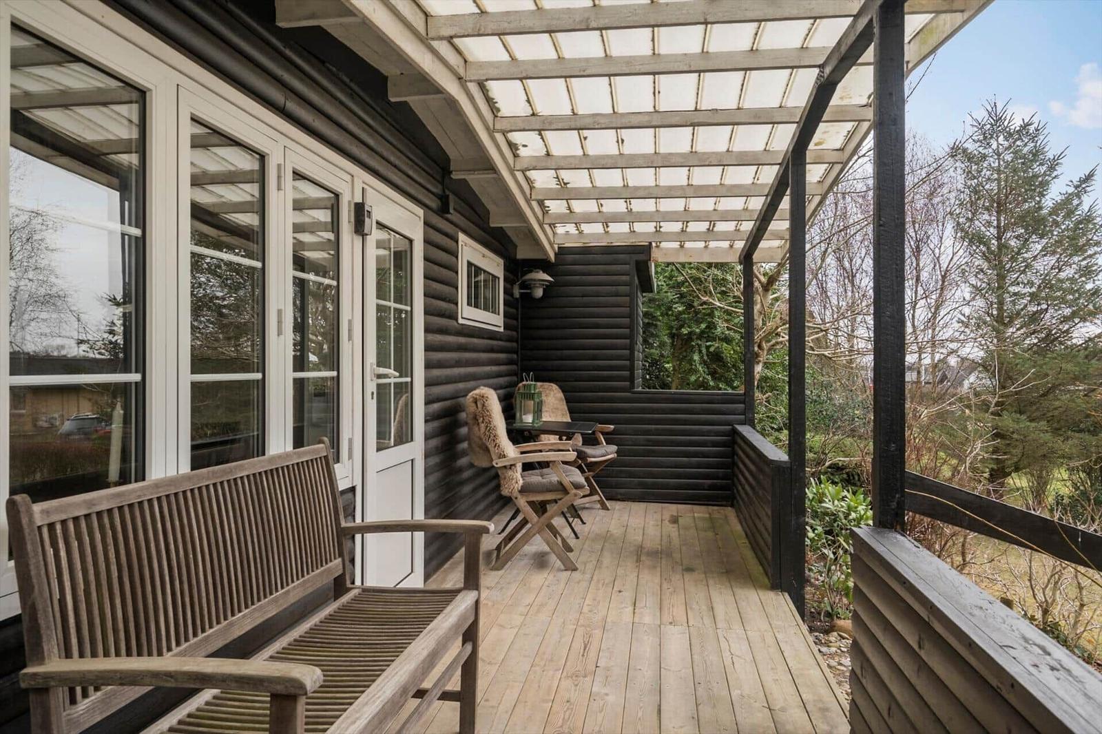 Terrasse mit Holzboden, Sitzgelegenheiten und Blick auf Grünflächen.