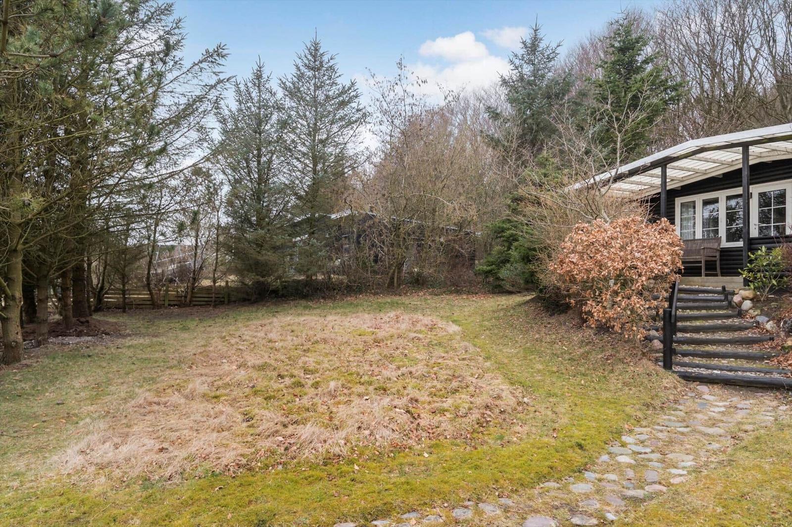 Haus mit Terrasse, Garten und Wald im Hintergrund.