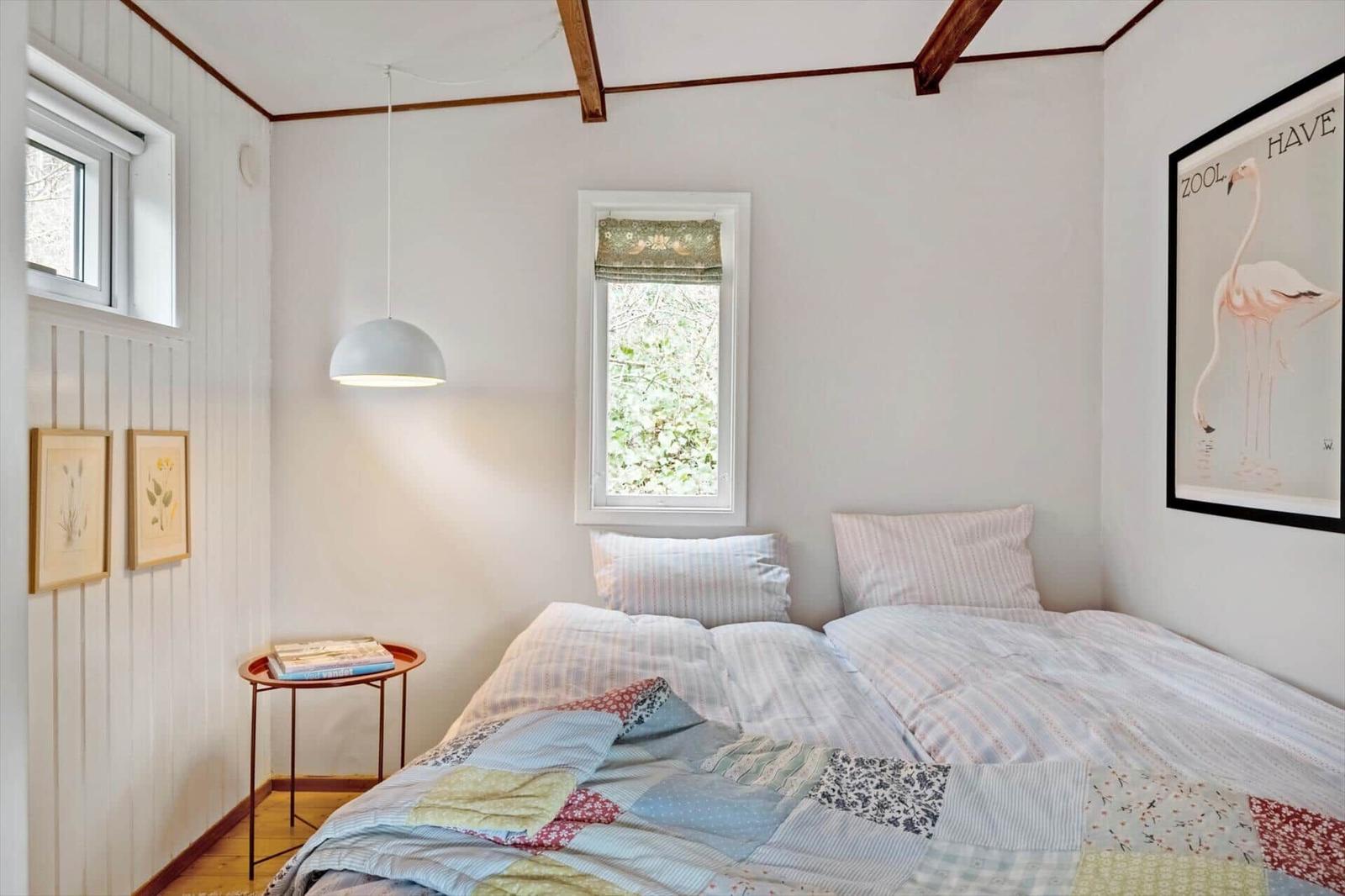 Schlafzimmer mit Bett, Fenster und Wandbild mit Flamingo.