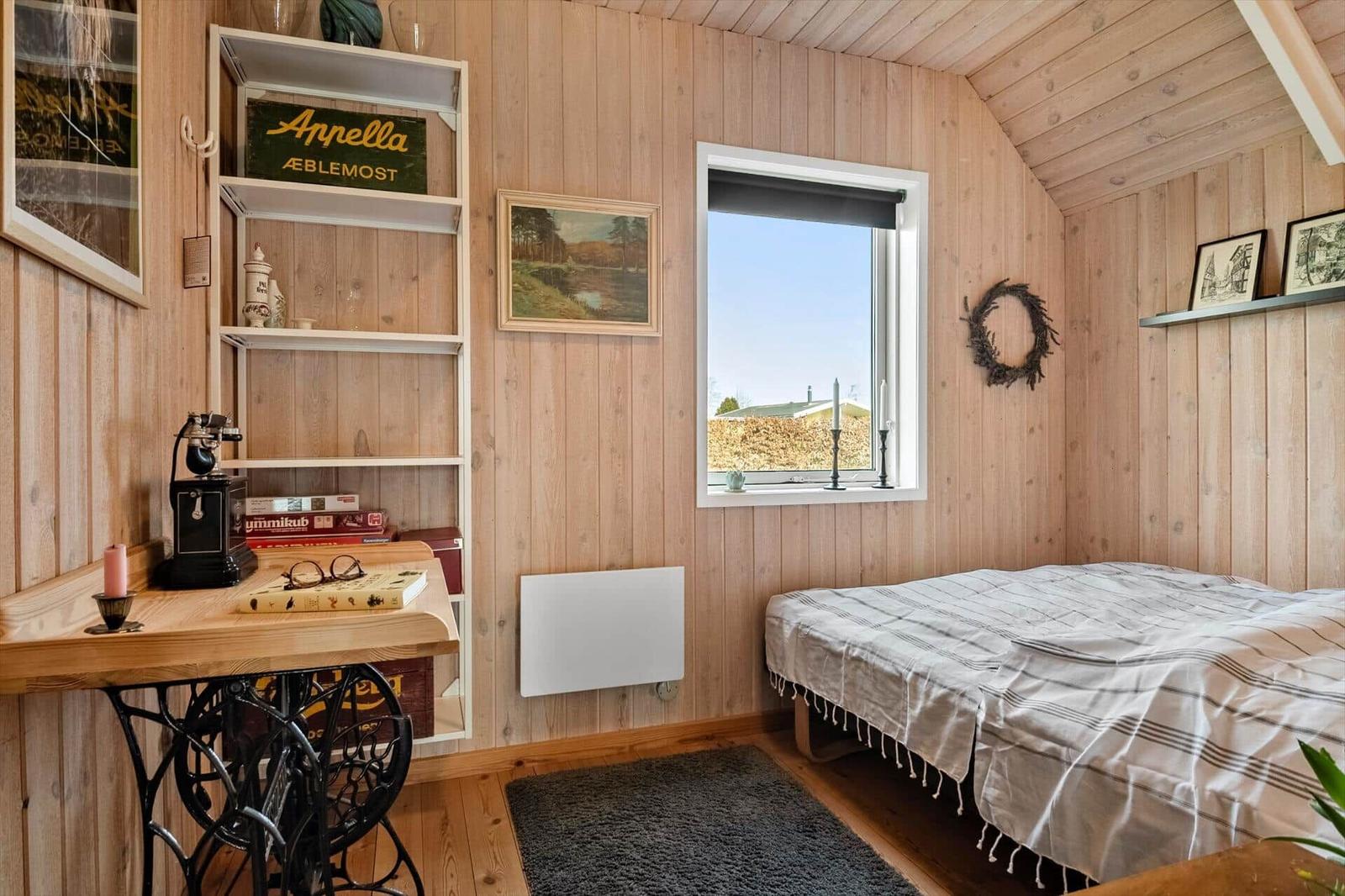 Schlafzimmer mit Holzwand, Bett, Schreibtisch und Fenster mit Blick.