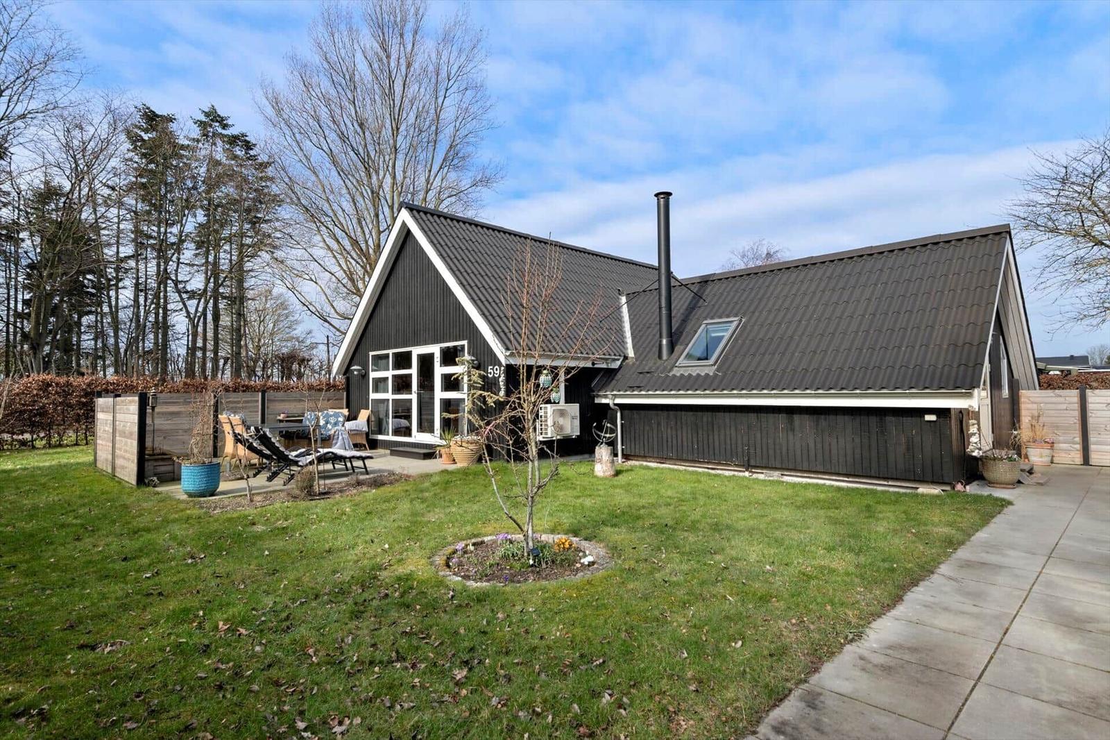 Schwarzes Haus mit Garten und Terrasse. Holzverkleidung und Dach aus Metall.