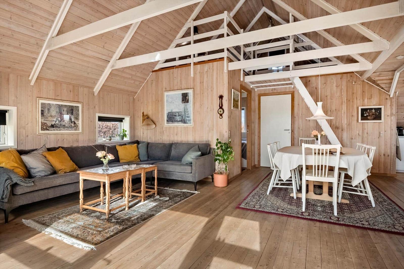 Wohn- und Essbereich mit Holzdecke, Sofa, Tisch und Stühlen.
