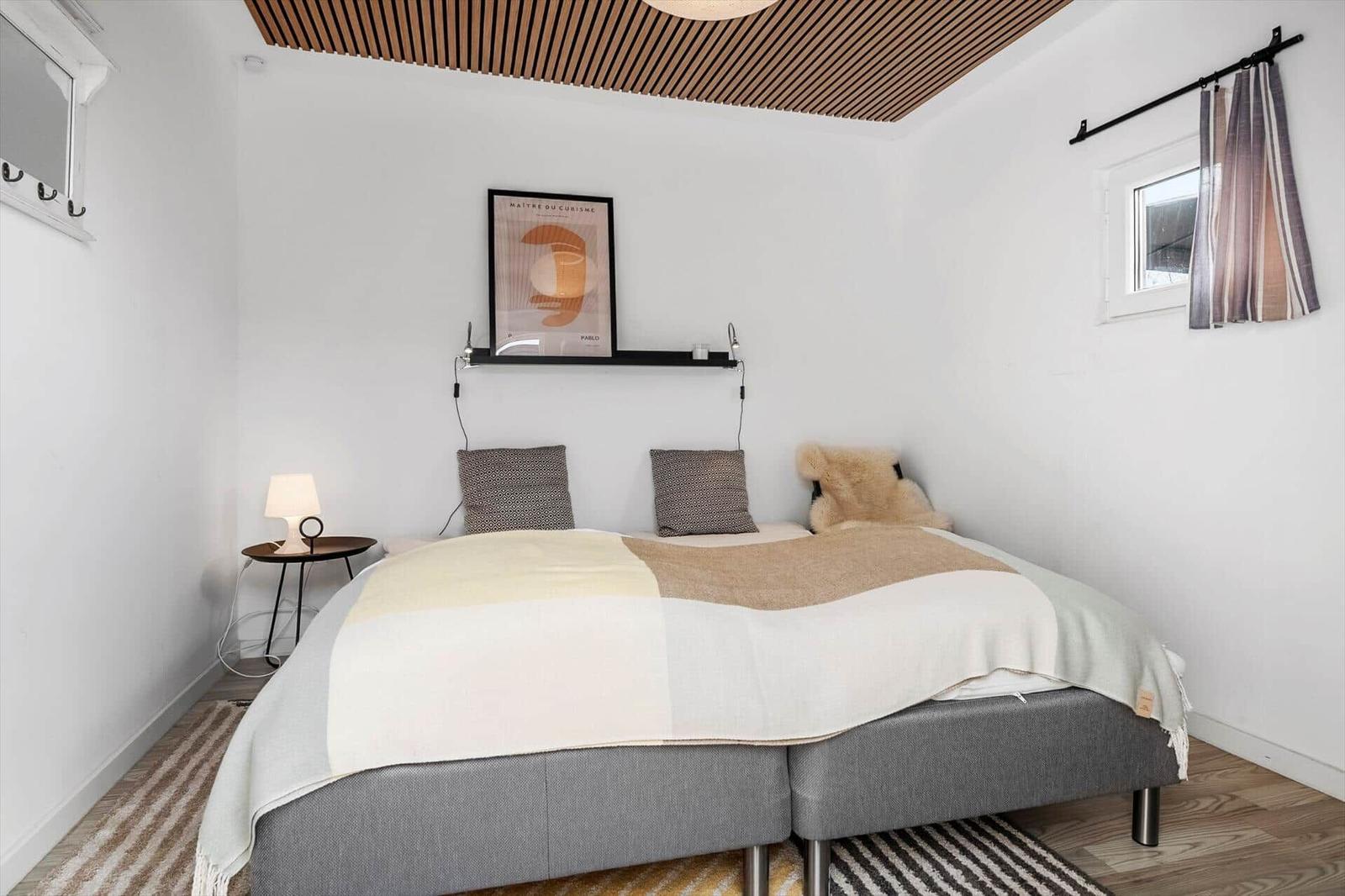 Schlafzimmer mit Bett, Wandbild und Holzdecke.