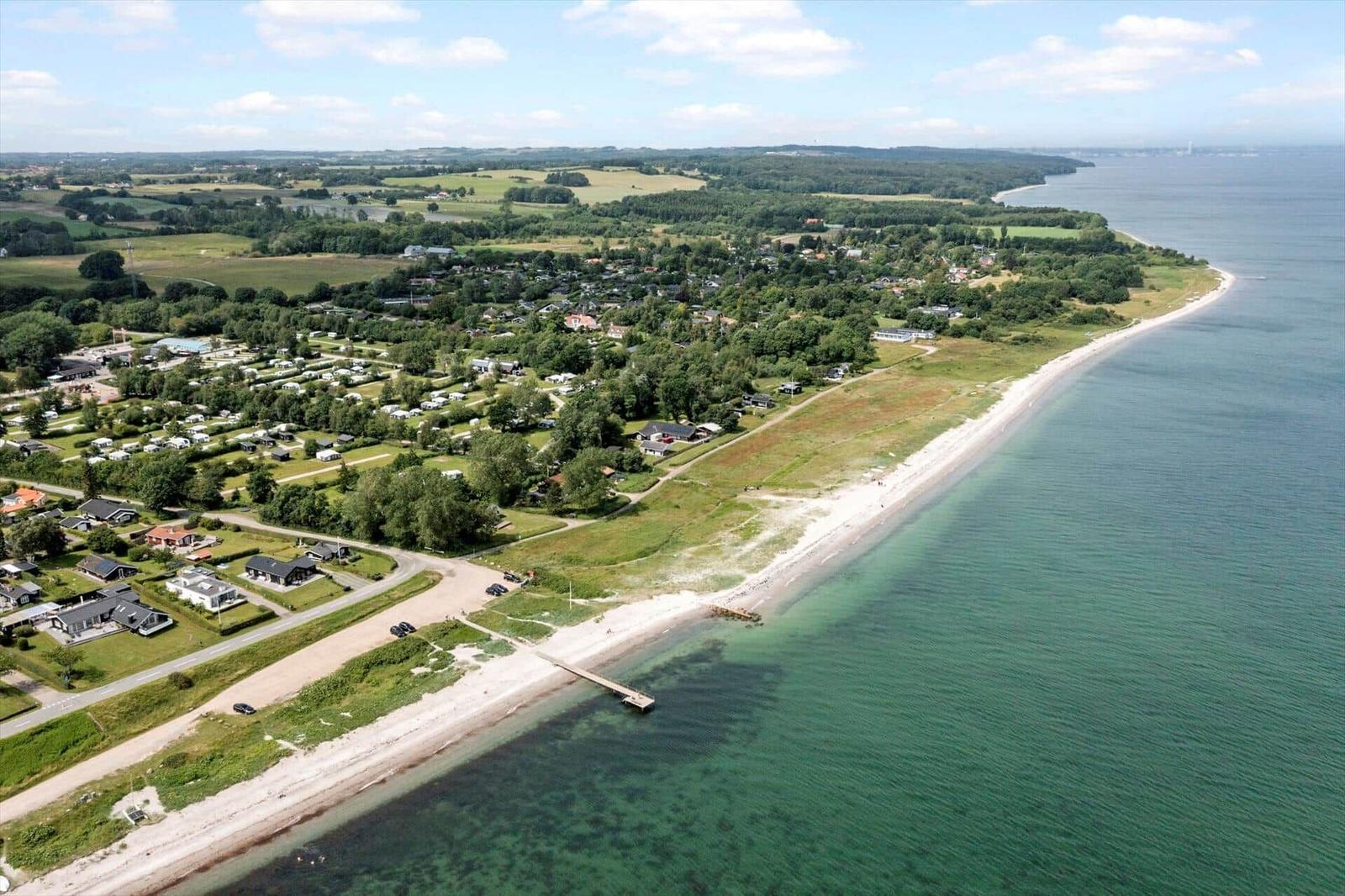Strandort mit Ferienhäusern und Grünflächen entlang der Küste.