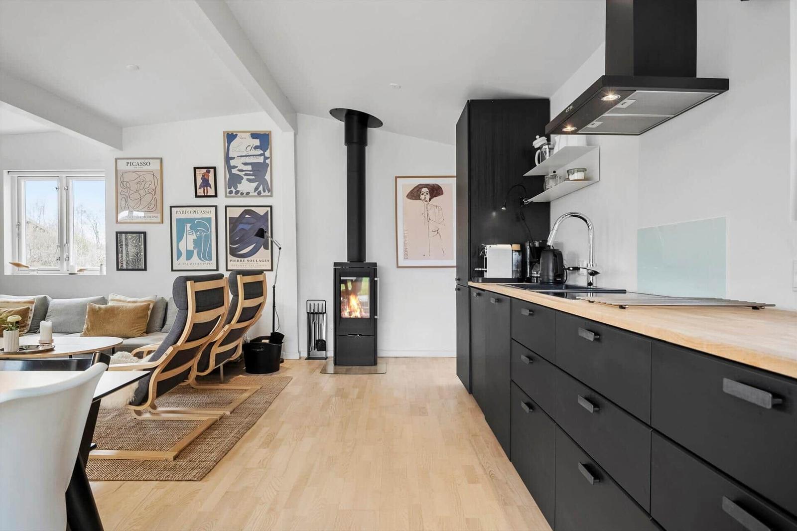 Wohnküche mit Holzboden, Kaminofen und Kunstwerken an der Wand.