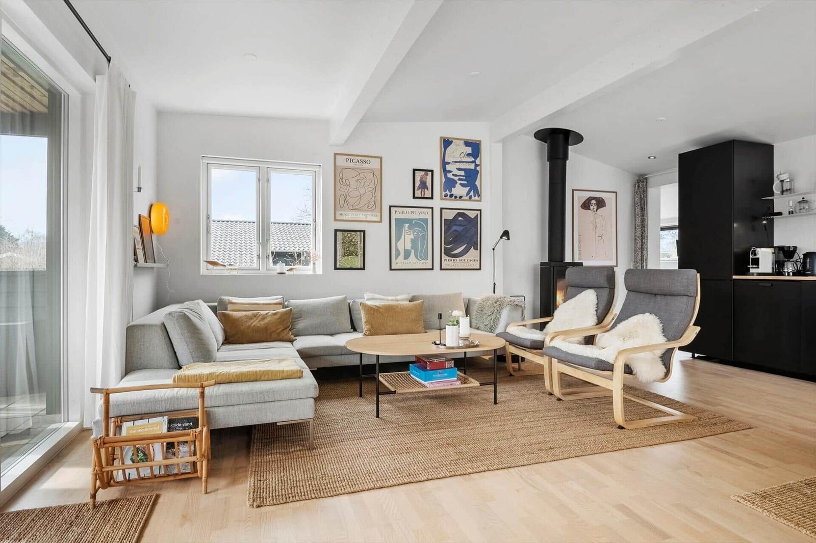 Wohnzimmer mit Sofa, Sesseln, Kamin und Wandbildern.