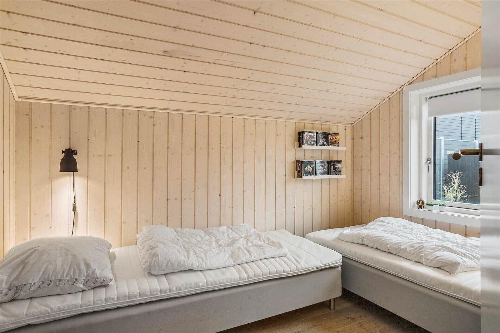 Zwei Betten mit weißen Bettwäsche in einem holzvertäfelten Zimmer mit Fenster.