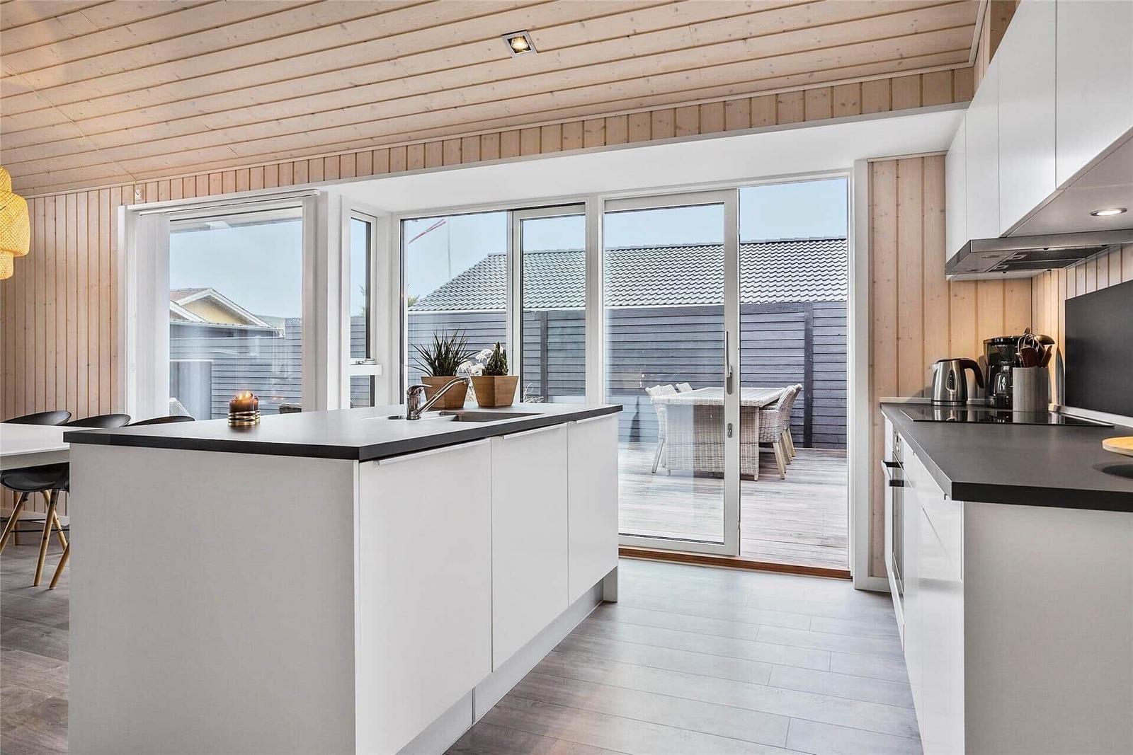 Küche mit Insel, Glasfront zum Balkon und Holzdecke.