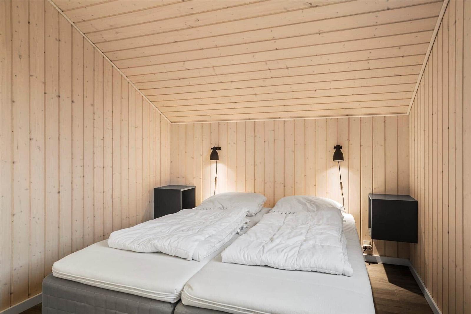 Schlafzimmer mit zwei Betten, Holzwand und Nachttischen