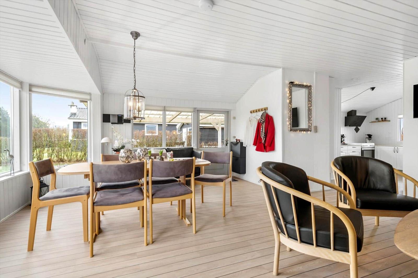 Essbereich mit Tisch und Stühlen, Sitzgelegenheiten und Blick auf Garten.