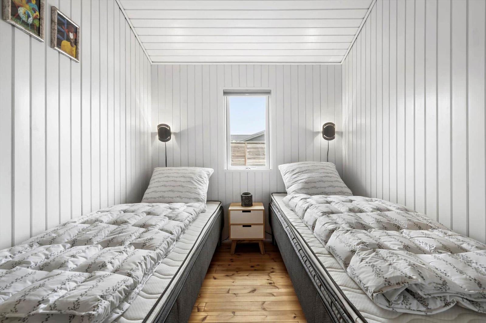Zwei Betten mit gemusterten Bettdecken, Holzboden und Fenster im Schlafzimmer.
