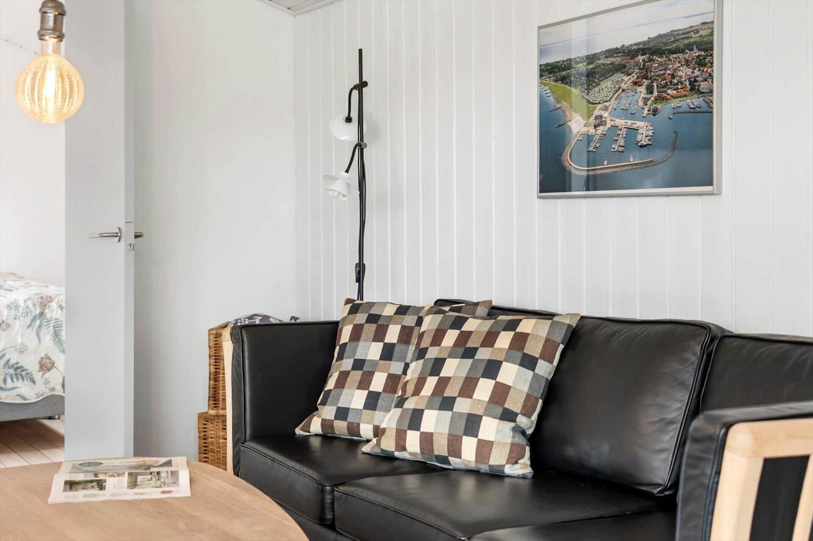 Schwarzes Sofa mit karierten Kissen, Wandbild und Stehlampe im Wohnzimmer.