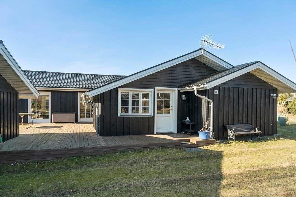 Wooden house with deck and garden. White windows and door.