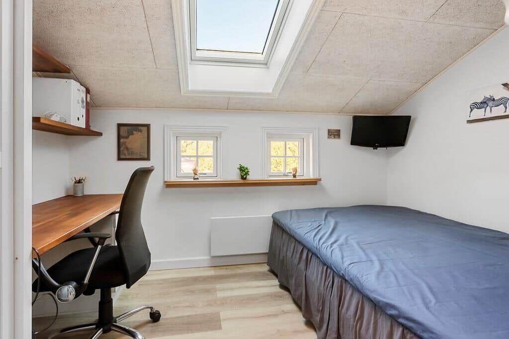 Bedroom with bed, desk, TV, and skylight.