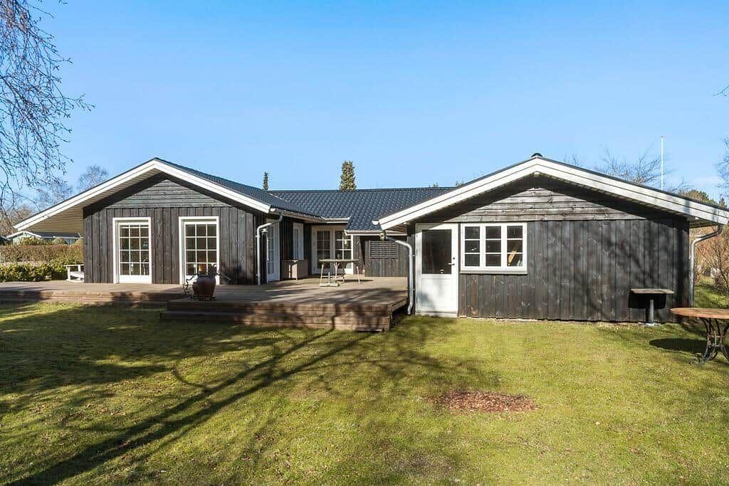 Wooden house with terrace and garden. White windows and door.