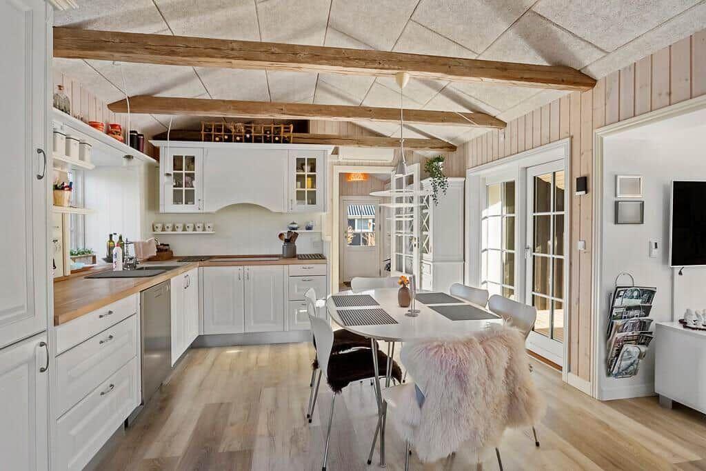 Kitchen with dining area, wooden beams, and glass doors to the outside.