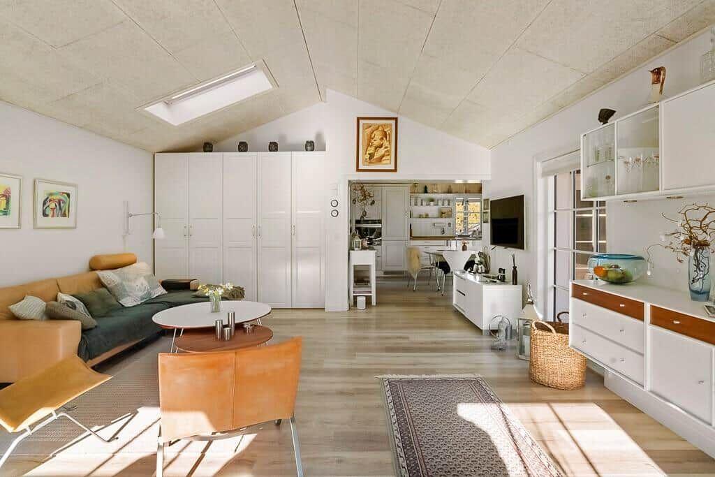 Living area with sofa, table, and kitchen area in the background.