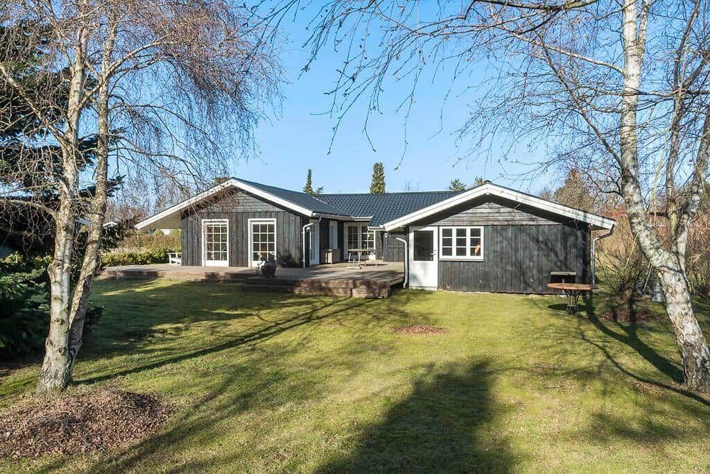 Wooden house with terrace and garden among trees