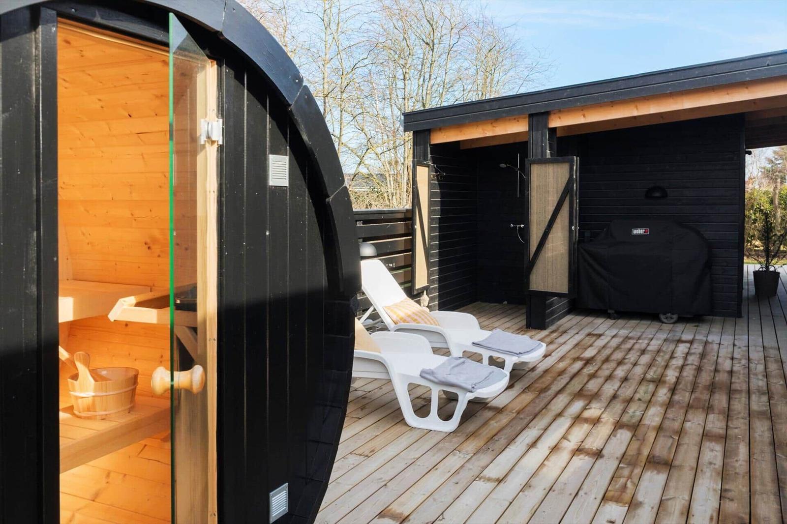 Outdoor area with sauna, lounge chairs, and shower on wooden deck.