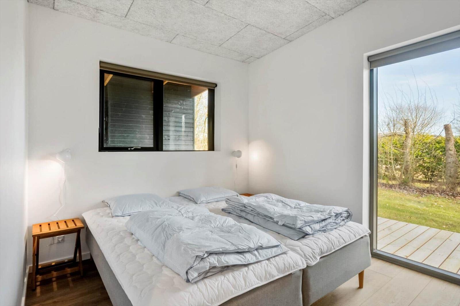 Bedroom with double bed, window, and glass door to terrace.