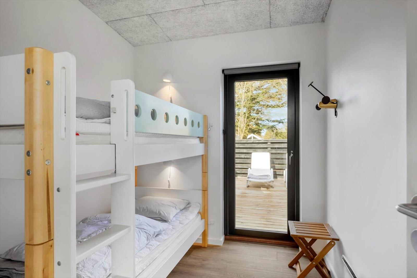 Room with bunk bed and door to terrace with lounge chair.