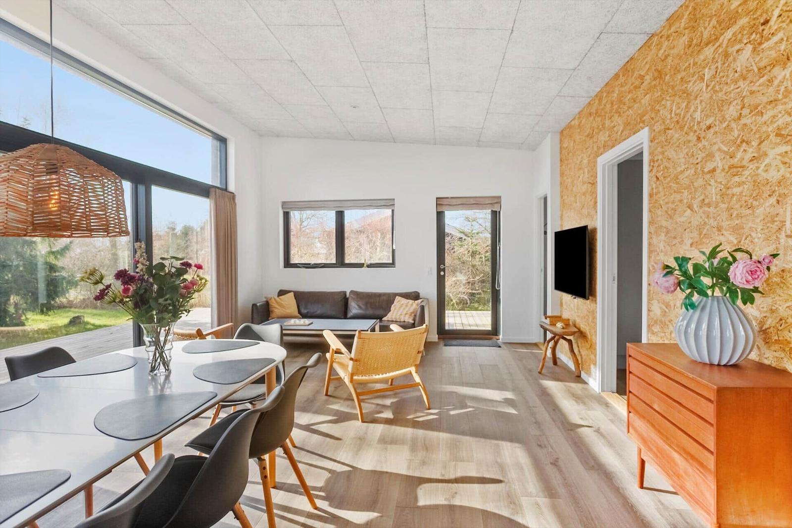 Living and dining area with wooden floor, large windows, and modern furnishings.