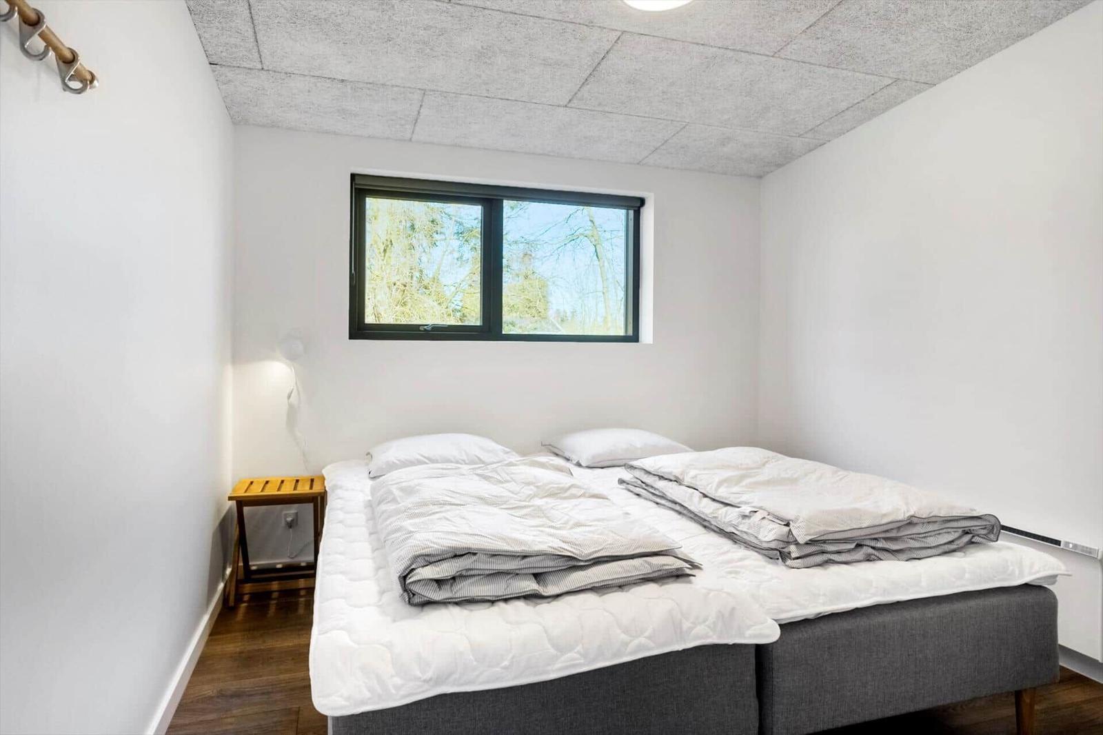 Bedroom with double bed, window, and nightstand.